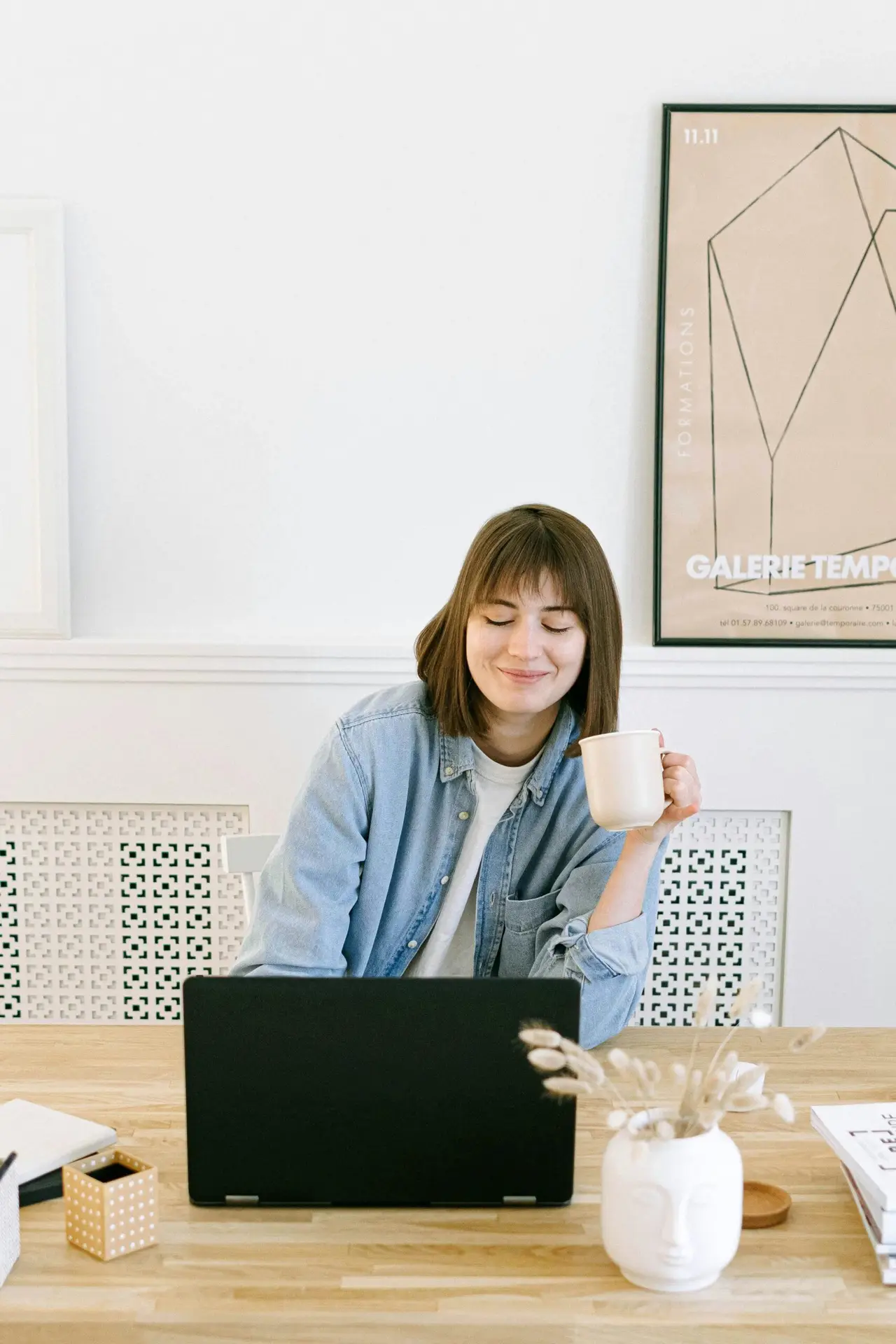 Blogs Woman in a home office setting, smiling with a coffee cup near a laptop.